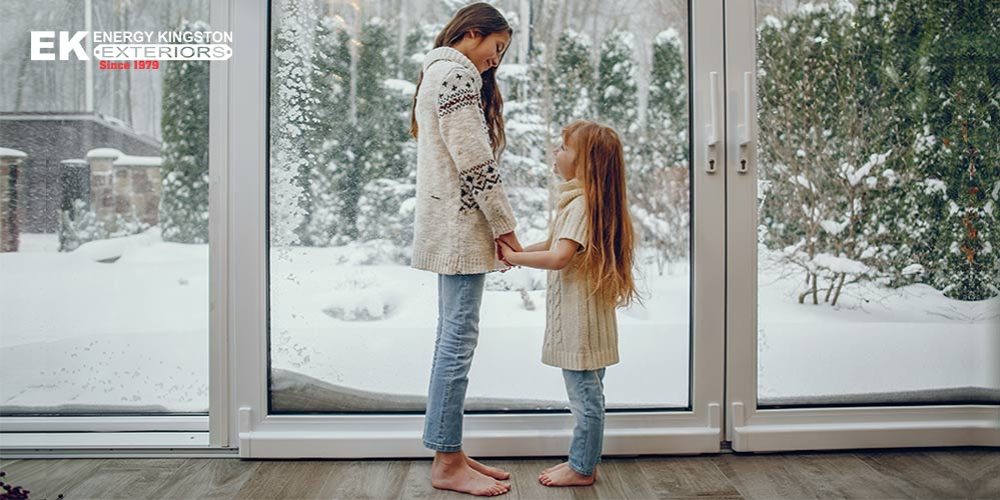 two girls standing in a warm heated sunroom with snow covered yard in background